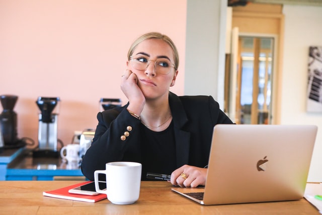 Business woman dressed in black glancing sideways and contemplating